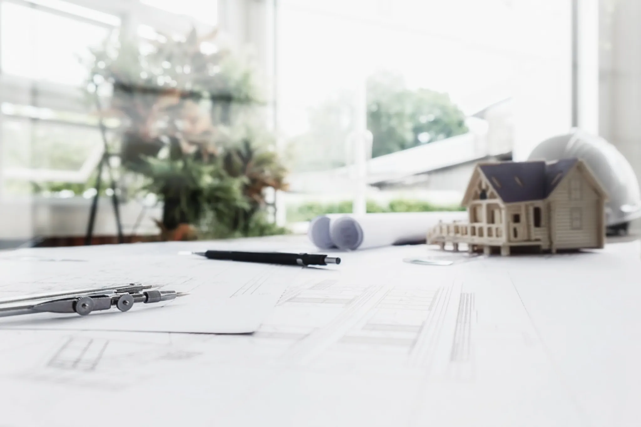 Architectural plans, drafting tools, and home model symbolizing the design-build process by Ntegrity Builders in Central Indiana.