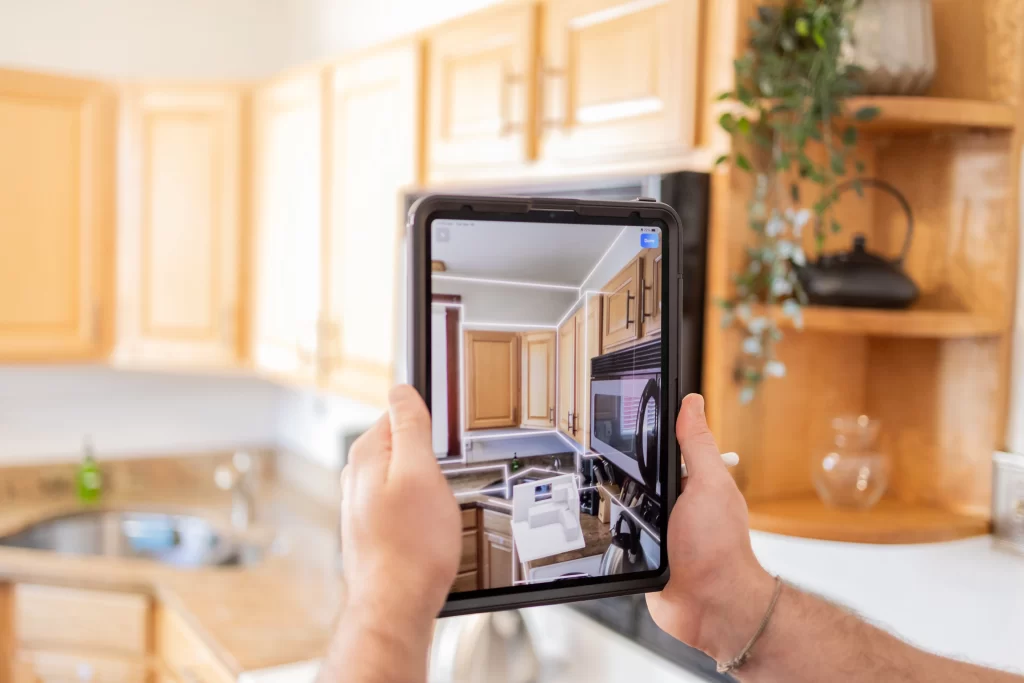 Person using a tablet to scan a kitchen for 3D rendering during the design phase with Rendr.