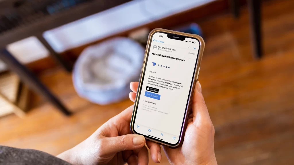 Person holding a smartphone showing a Rendr email invitation to begin 3D project capture.