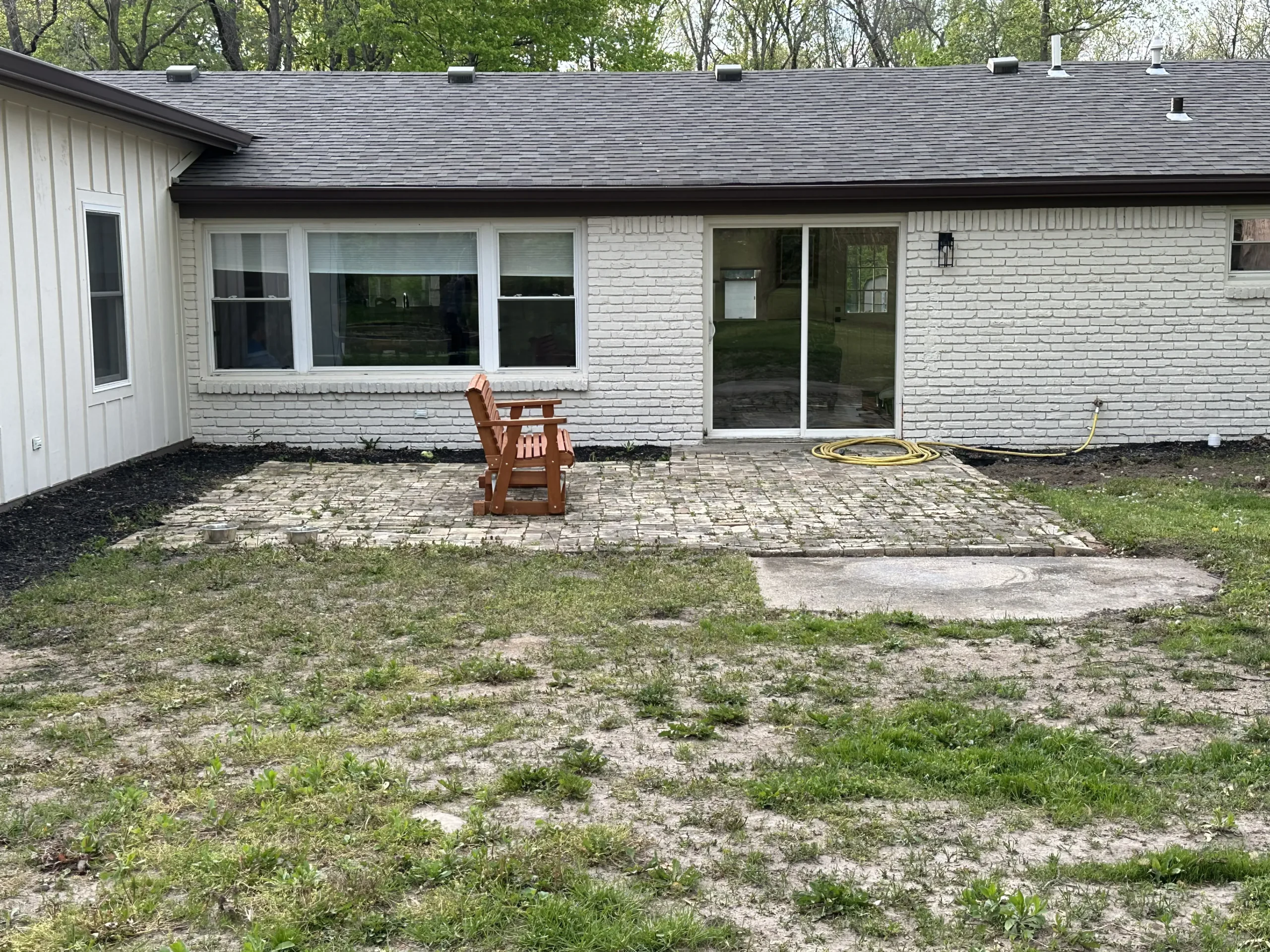 Worn paver patio before replacement with a stamped concrete patio and custom wood pergola in Carmel, Indiana.