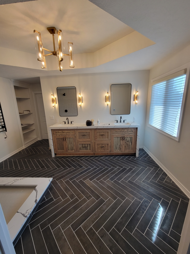 Primary bathroom remodel in Carmel Indiana with a custom white oak vanity, heated herringbone floor, and frameless glass shower