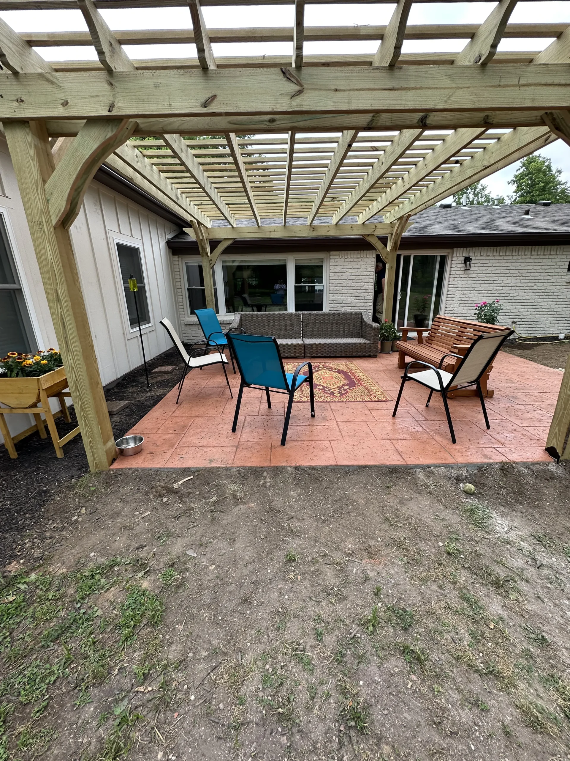 Furnished Terracotta stamped concrete patio beneath a custom wood pergola in Carmel, Indiana