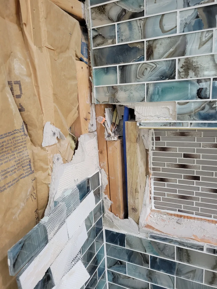 Open electrical box visible in the shower wall during demolition