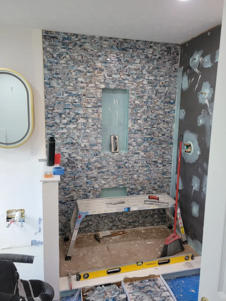 Blue tile being installed on the primary bathroom shower walls
