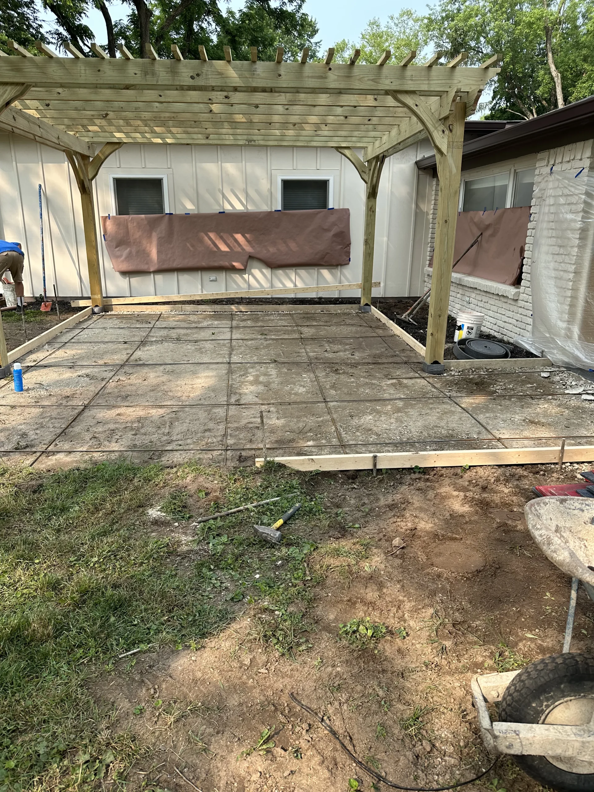Formwork and steel reinforcement prepared for an expanded stamped concrete patio beneath a custom wood pergola in Carmel, Indiana