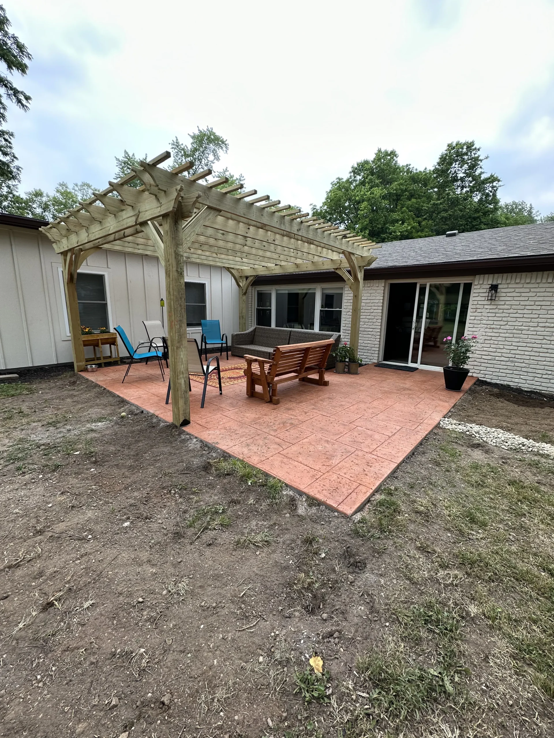 Completed Terracotta stamped concrete patio with custom wood pergola and drainage improvements in Carmel, Indiana