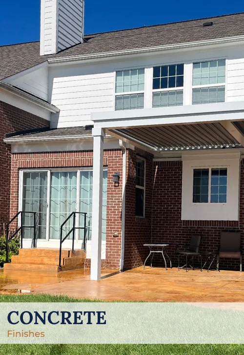 Finished decorative concrete patio beside brick home with covered outdoor structure and backyard seating area