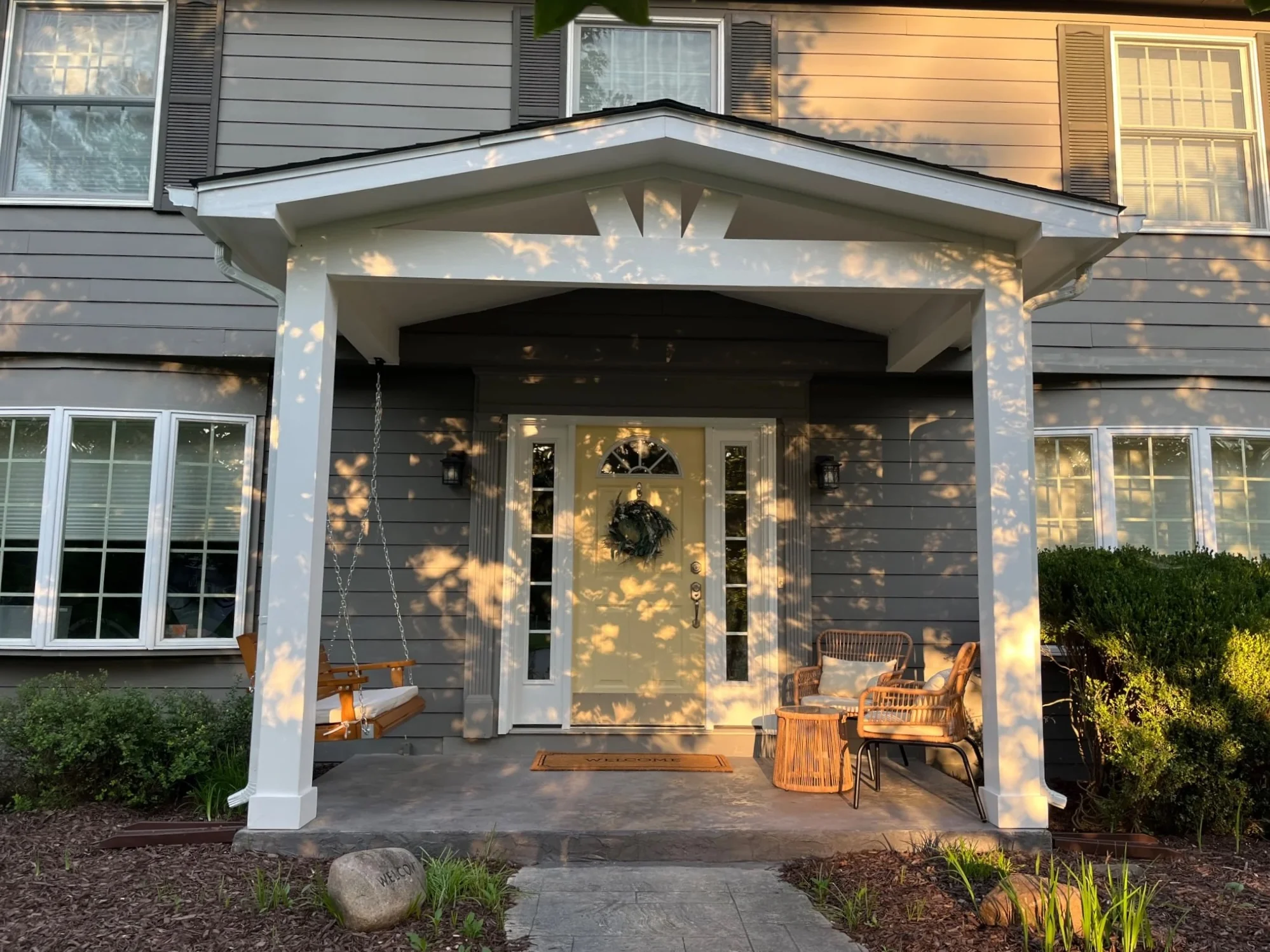 Straight-on evening view of finished covered front porch with seating in Carmel Indiana