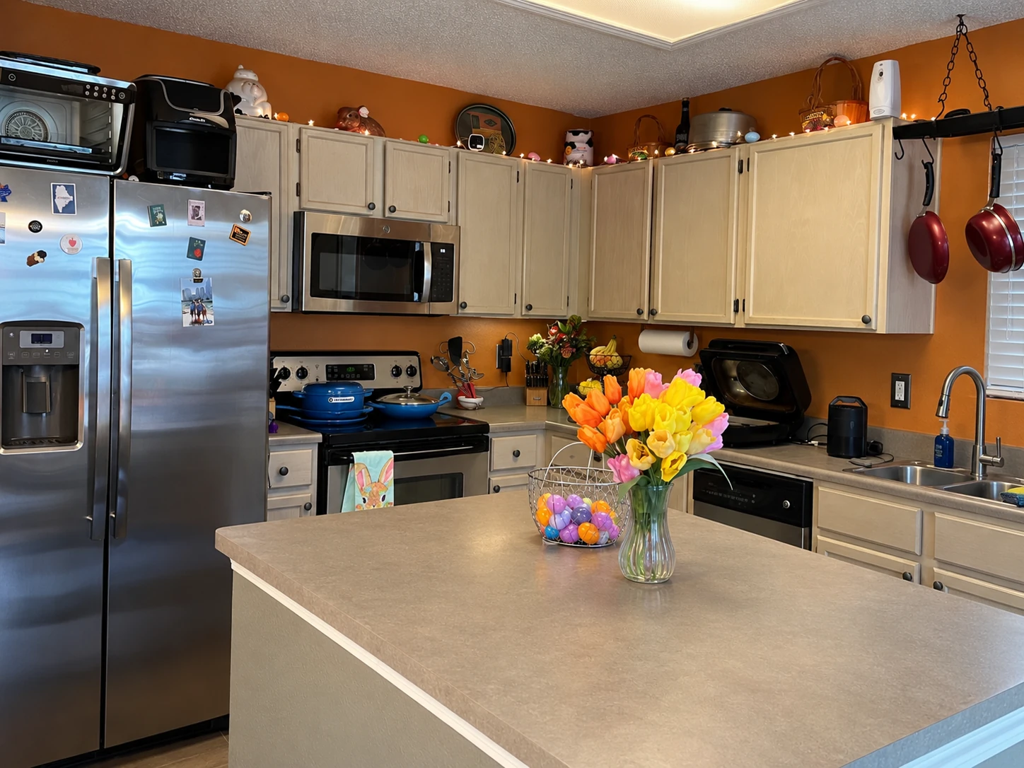 Original kitchen before remodel with light wood cabinets, laminate countertops, and orange walls in Fishers Indiana