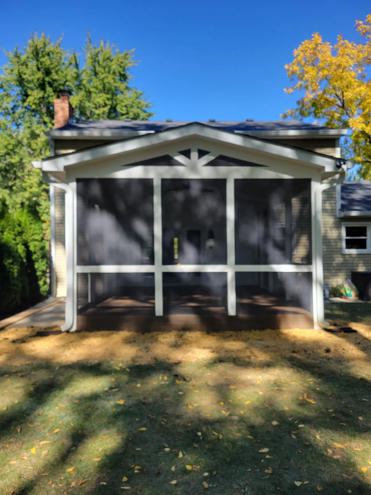 Front view of completed screened porch addition with dark screening, white framing, and a gabled roof in Carmel Indiana.