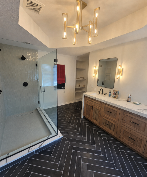 Primary bathroom remodel in Carmel with a glass shower, custom white oak vanity, and heated wood-look herringbone tile floor