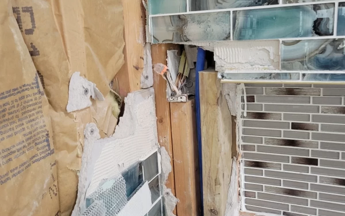 Demo photo showing unsafe junction box hidden behind shower tile during Carmel master bathroom remodel