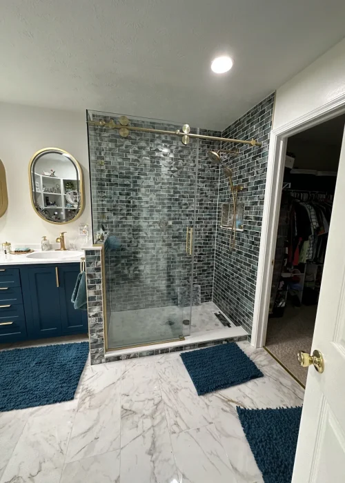 Prior-remodel primary bathroom with a glass shower, blue vanity, and marble-look floor tile