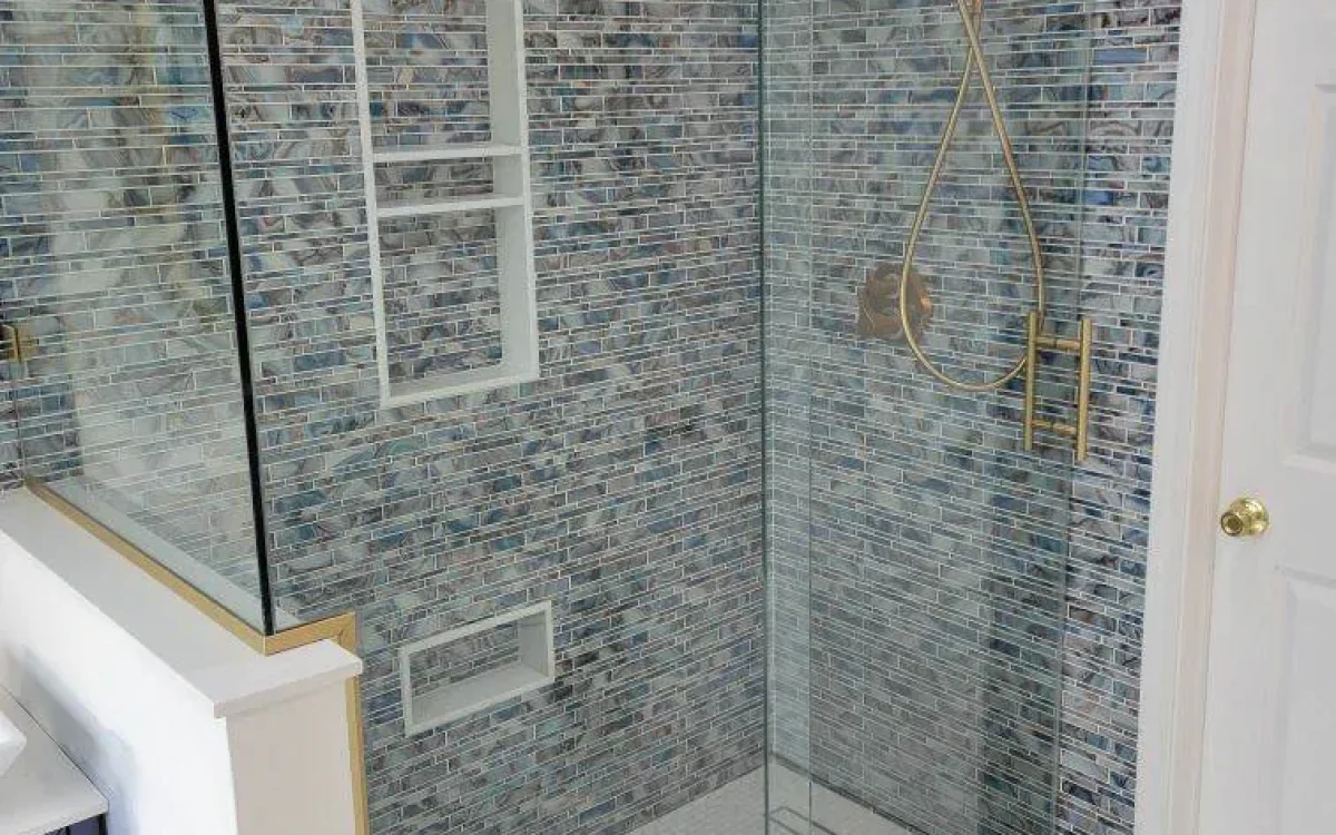 Finished glass-enclosed shower with blue wall tile, two niches, and gold-tone fixtures